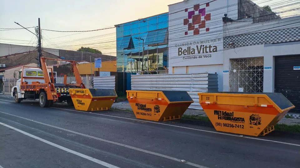 Caçambas laranja da Ideal Ferragista enfileiradas na rua em Santa Inês com o caminhão ao fundo