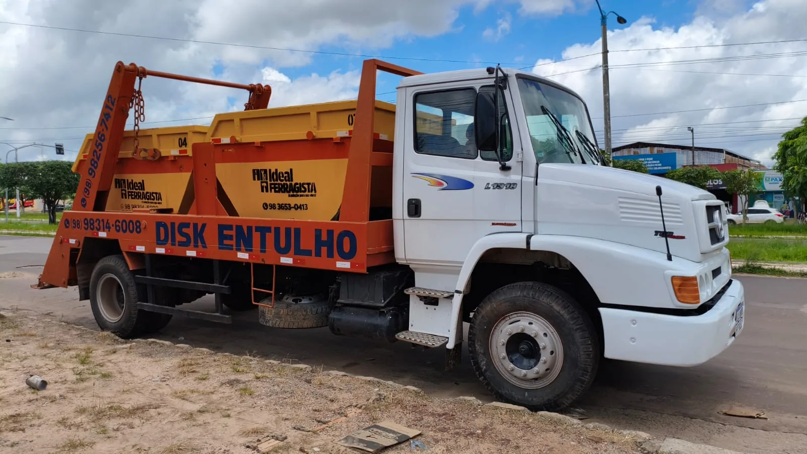 Caminhão poliguindaste Disk Entulho da Ideal Ferragista carregando uma caçamba laranja em Santa Inês